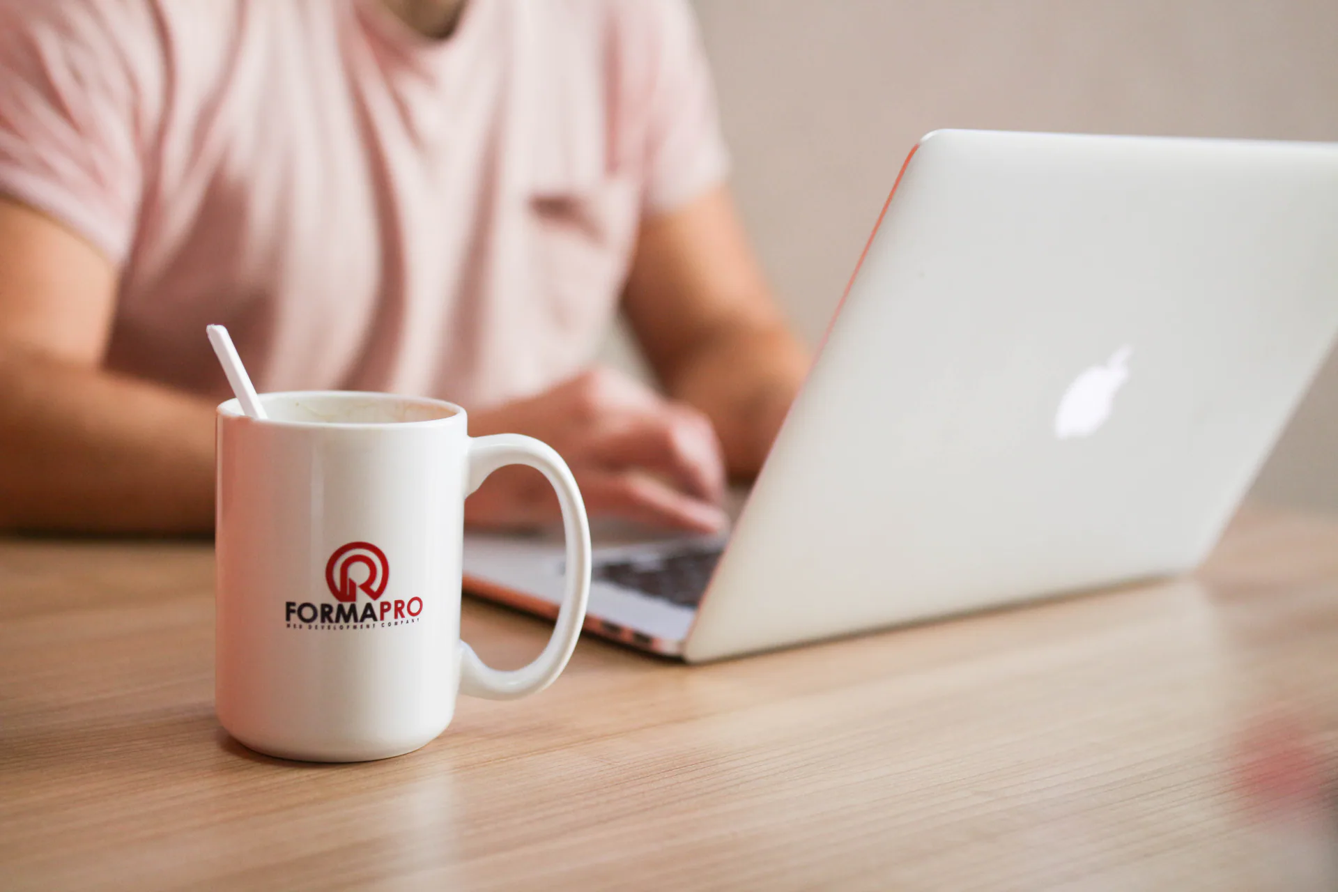 A person working at a laptop beside a Forma Pro mug